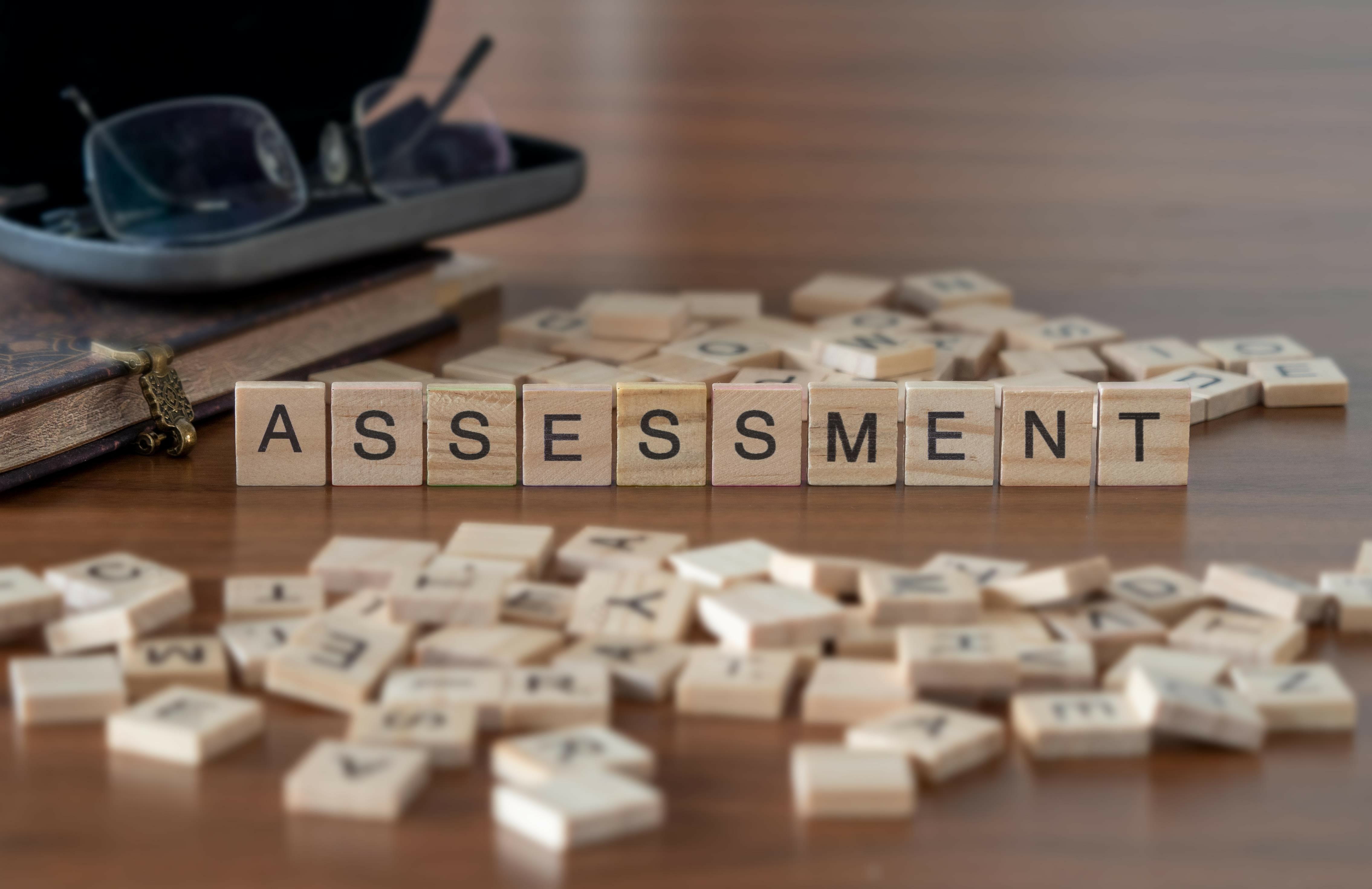 The word assessment spelled out with scrabble tiles